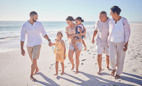 沙滩上的孩子摄影照片_大家庭在暑假、沙滩度假时牵手走在海滩上，表达爱、支持和关怀。