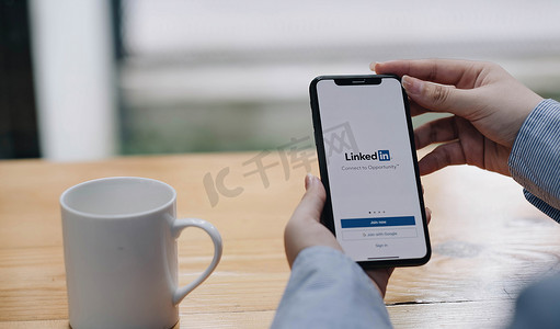 泰国清迈，2022 年 7 月 27 日：一位女士拿着苹果 iPhone X，屏幕上显示 LinkedIn 应用程序。LinkedIn 是一款智能手机照片共享应用程序。