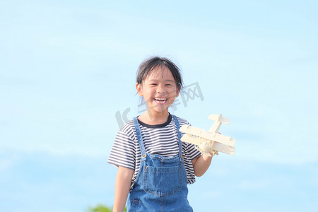 快乐的孩子在蓝色的夏日天空背景下玩玩具飞机。