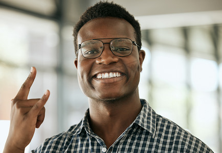 年轻的非洲裔美国商人戴着眼镜，在办公室里摆出喇叭或摇滚手势。