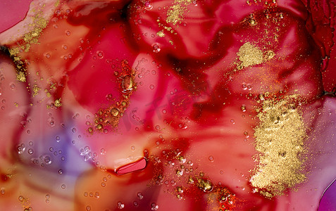 深红色水彩墨水在透明液体下沾上气泡和金色颗粒。