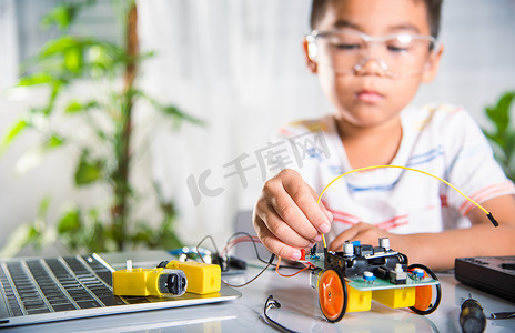 亚洲男孩用 Arduino 机器人车将能量和信号电缆插入传感器芯片
