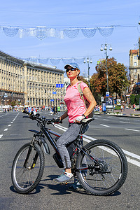 基辅摄影照片_一位骑着山地电动自行车的年轻女士站在基辅赫雷夏蒂克街的路上。
