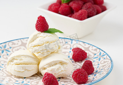 白色冰淇淋球摄影照片_圆盘中的香草冰淇淋球和红树莓