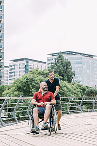 坐在轮椅上的男人和他的朋友在城市里散步