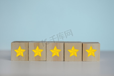 背景和复制空间上带有黄色五星符号的木制立方体。客户体验、满意度和最佳优质服务评级概念。