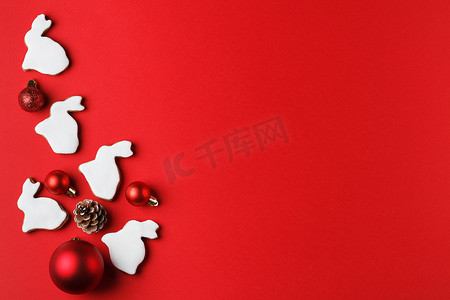 2023喜庆摄影照片_兔子形状的美味姜饼和红色背景的圣诞装饰。