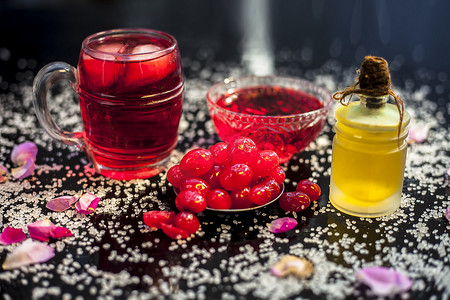 果浆摄影照片_新鲜甜樱桃或李属鸟的特写镜头，其油、果汁和茶在黑色光泽的表面上，配有生新鲜樱桃。