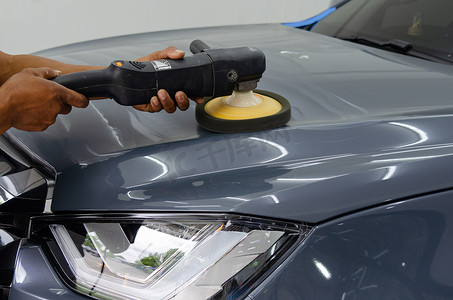 男子手持工具抛光机械师汽车修理，在车库洗车工作中详细介绍引擎盖汽车划痕维护。
