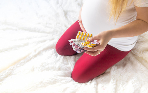 一名孕妇手里拿着许多药片。