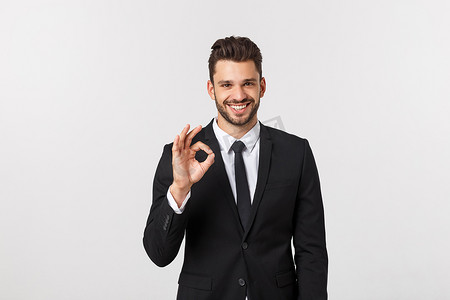 英俊的微笑商人用手指在灰色的背景下显示 ok 的手势。