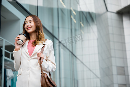 女商人拿着咖啡杯外卖去上班她走在她的办公楼附近