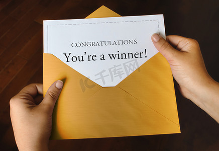 winner摄影照片_一个打开的闪亮金色信封，信封上写着 Congratulations Youre a winner！