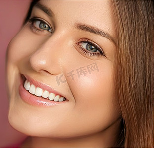 粉红色背景中的美容、化妆和护肤化妆品模特脸像、自然妆容的微笑女性、完美健康的牙齿、牙科护理