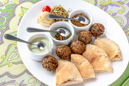 传统中东自制菜肴沙拉三明治、皮塔饼、鹰嘴豆泥和鹰嘴豆，配上木桌上的蔬菜和香料