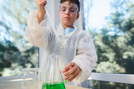 细节：化学课上，一名男学生的手将几滴绿色化学溶液滴入试管中