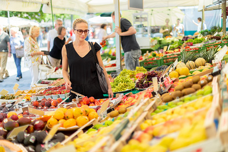 在当地食品市场购买水果和蔬菜的妇女。