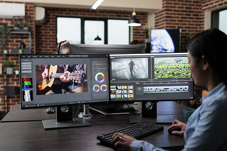 创意公司专业电影镜头编辑坐在多显示器工作站，同时编辑电影帧。
