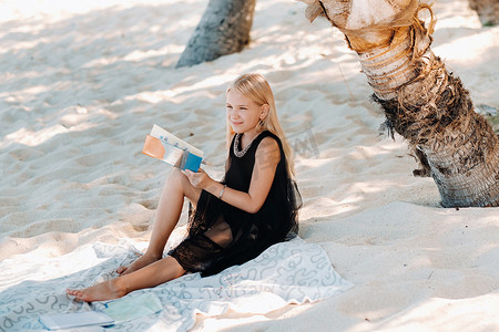 一个女生摄影照片_一个小女孩坐着享受毛里求斯莫纳山的热带海滩。一个女孩在毛里求斯的海滩上读书