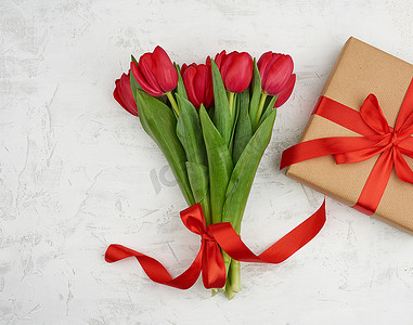 一束红色盛开的郁金香，绿叶，包裹着的礼物我