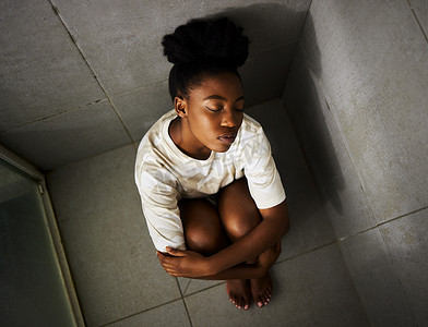 心理治愈摄影照片_有心理健康问题的抑郁、焦虑和悲伤的女孩独自坐在淋浴中思考，同时感到情绪激动。