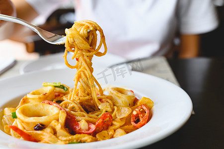 在意大利餐厅用叉子吃海鲜意大利面白酱的女人。