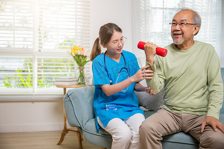 年轻护士理疗师支持老年老人在家举哑铃
