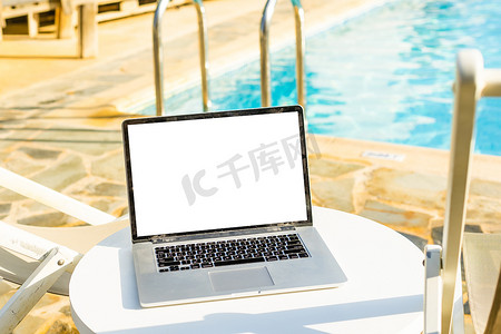 五一幕布摄影照片_在阳光明媚的天气里，一台屏幕空白的笔记本电脑矗立在一个美丽的家庭花园的庭院里。