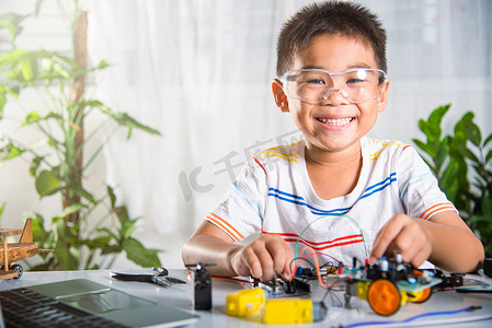 亚洲男孩用 Arduino 机器人车将能量和信号电缆插入传感器芯片