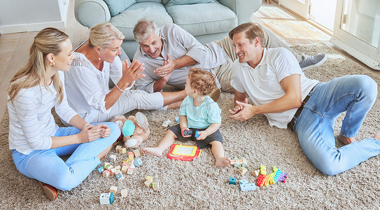 客厅里摄影照片_家人在客厅里与婴儿一起玩耍，以在地毯上进行教育和认知发展。