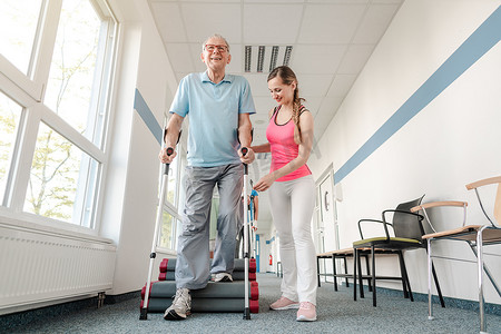康复中的老年人学习如何拄拐杖行走