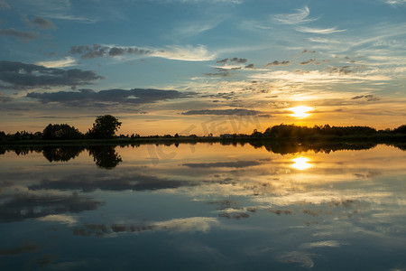 蓝色湖水摄影照片_日落时湖水中云的镜面反射