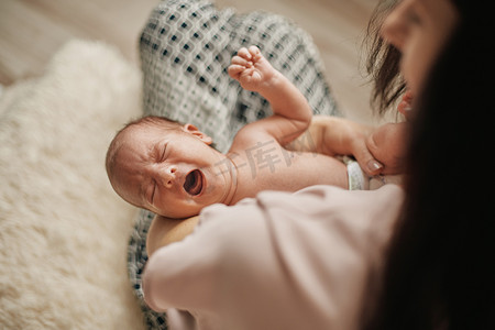 新生儿在妈妈怀里饿哭。