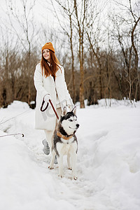 开朗的女人冬装在雪地里遛狗寒假
