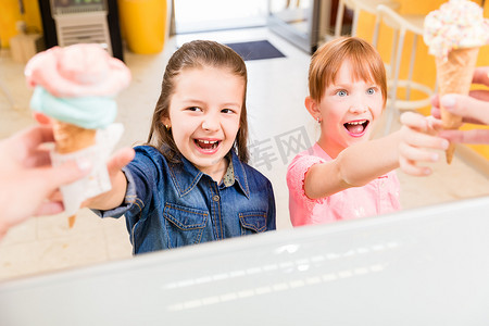 儿童冰淇淋摄影照片_孩子们在柜台拿冰淇淋