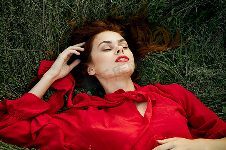 穿红裙子的女人躺在草地上致辞时尚夏日