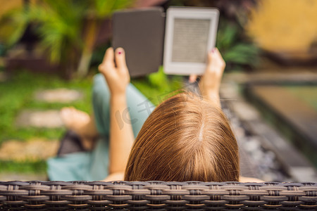 女人在花园的躺椅上看电子书