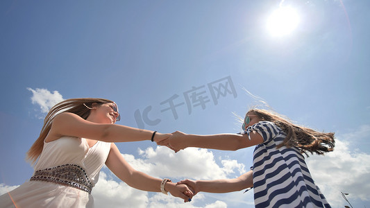 在温暖的夏日里，快乐的女朋友们挽着胳膊旋转。