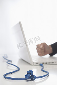 白色背景下用打结电缆手击笔记本电脑键盘的特写侧视图