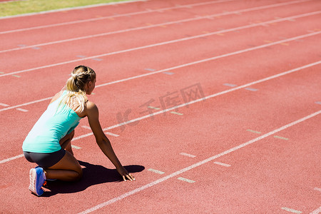 在阳光下奔跑摄影照片_女运动员准备在跑道上奔跑