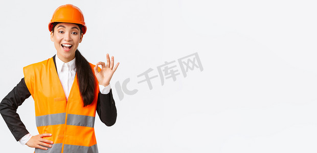 满意快乐的亚洲女工程师、安全头盔和反光夹克的施工经理表现出满意的姿态，保证建筑质量，确保一切都很好