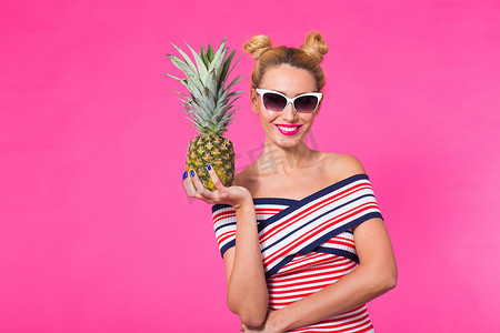 粉红色背景中戴太阳镜和菠萝的时尚夏季肖像女性