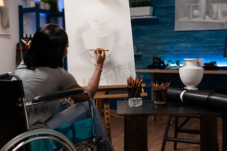 美术生摄影照片_坐轮椅的美术生在画布上素描花瓶