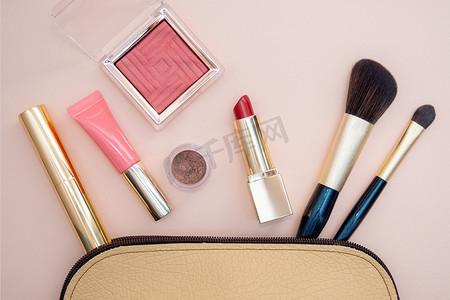 粉红色背景下米色化妆包中化妆品的顶部视图