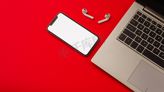 苹果x摄影照片_俄罗斯图拉 — 2019 年 5 月 24 日：红色背景中的苹果 iphone X 和 Airpods，带笔记本。