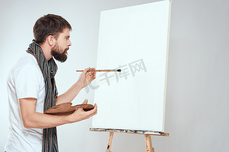 男性艺术家在画架调色板艺术创意浅色背景上绘画