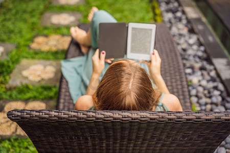 看电子书摄影照片_女人在花园的躺椅上看电子书