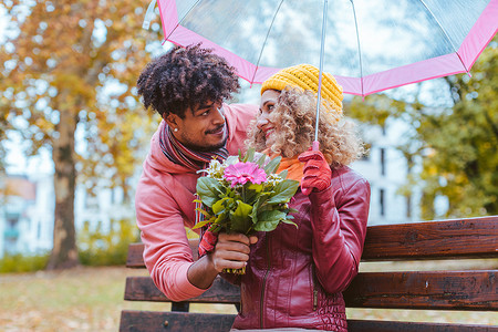 男人在一个毛毛细雨的秋日用一束鲜花给妻子惊喜