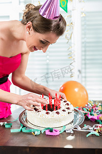 微笑标语摄影照片_一个美丽的女人微笑着把红蜡烛放在蛋糕上的肖像