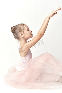 古典芭蕾舞摄影照片_穿着粉红色舞蹈服装芭蕾舞足尖鞋芭蕾舞短裙浅色背景模型的女孩芭蕾舞演员
